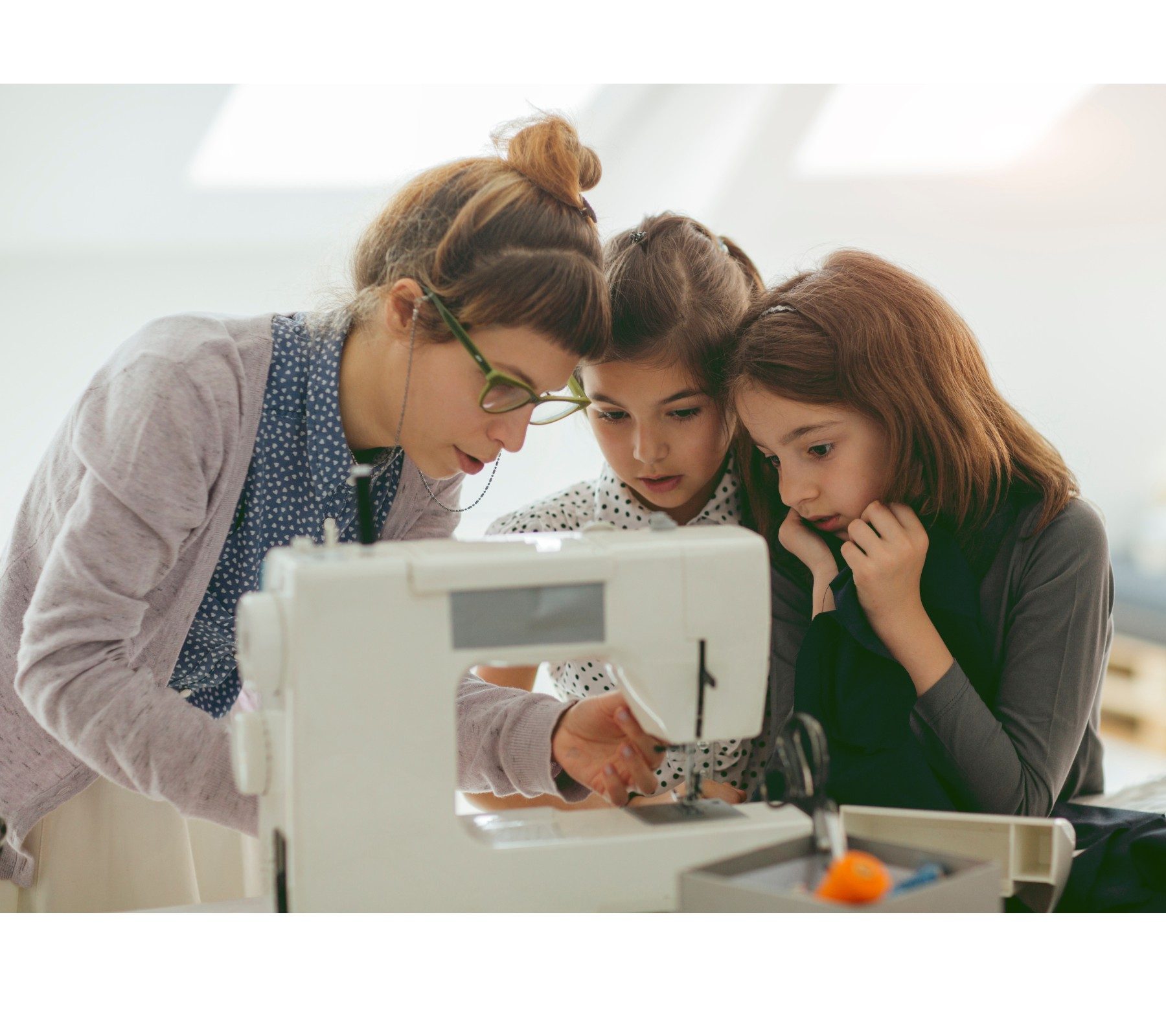 Two young girls learning how to sew from older lady