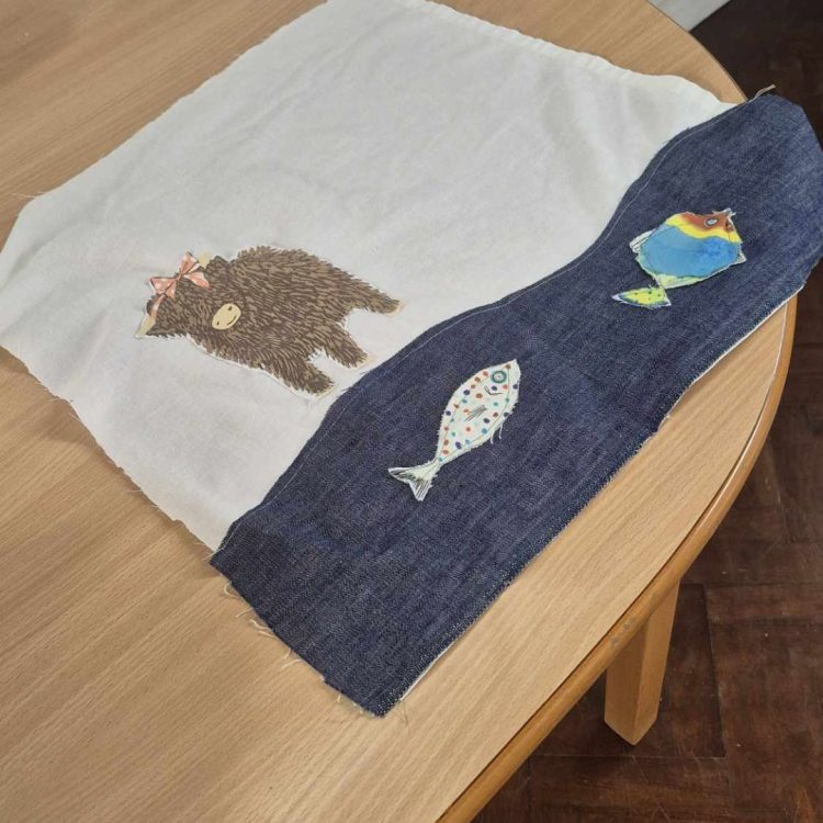 Cushion cover with highland cow and fish sewn on.