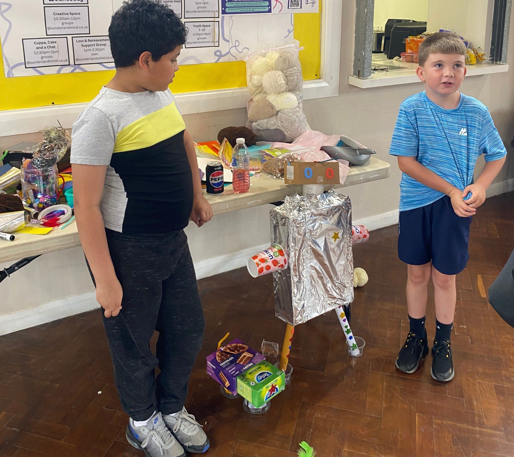 2 young people who are Youth Space Members with a robot they made.