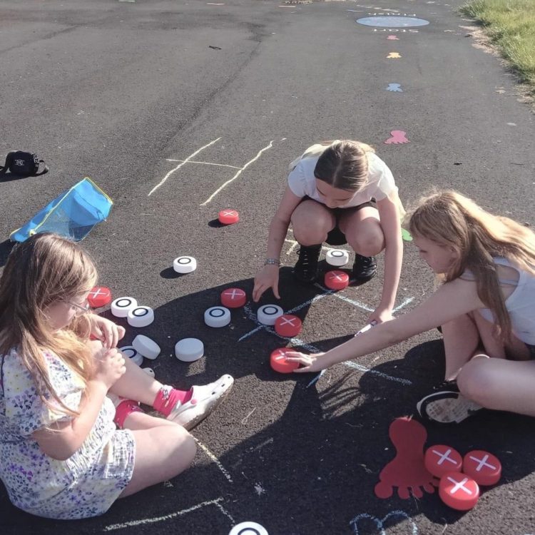Youth Space members, three girls playing noughts and crosses outside