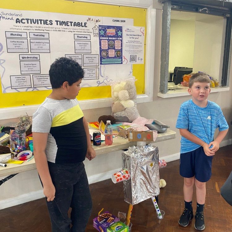 2 young people who are Youth Space Members with a robot they made.