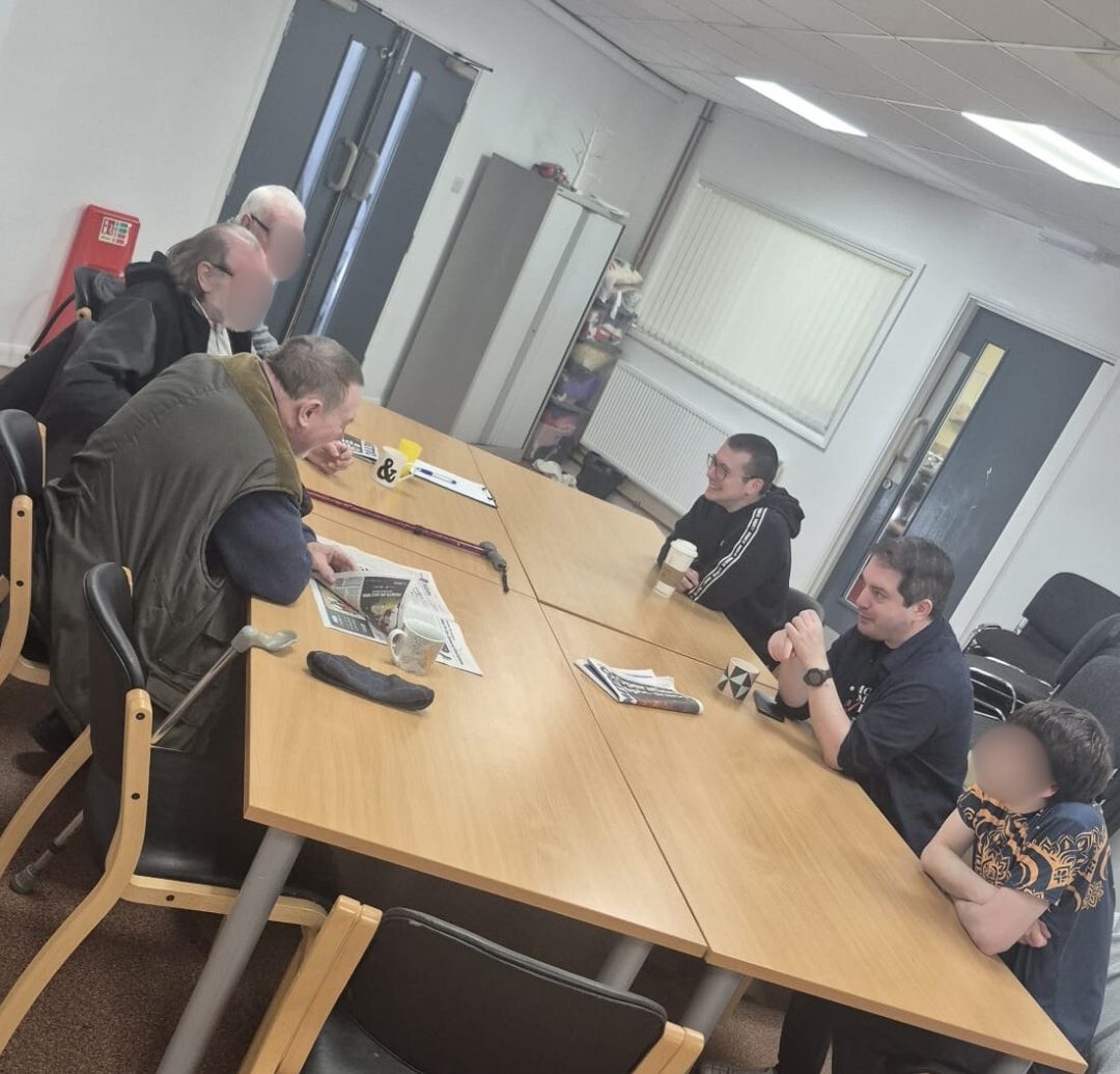 Six Men's Group Members sat round the table laughing and talking.