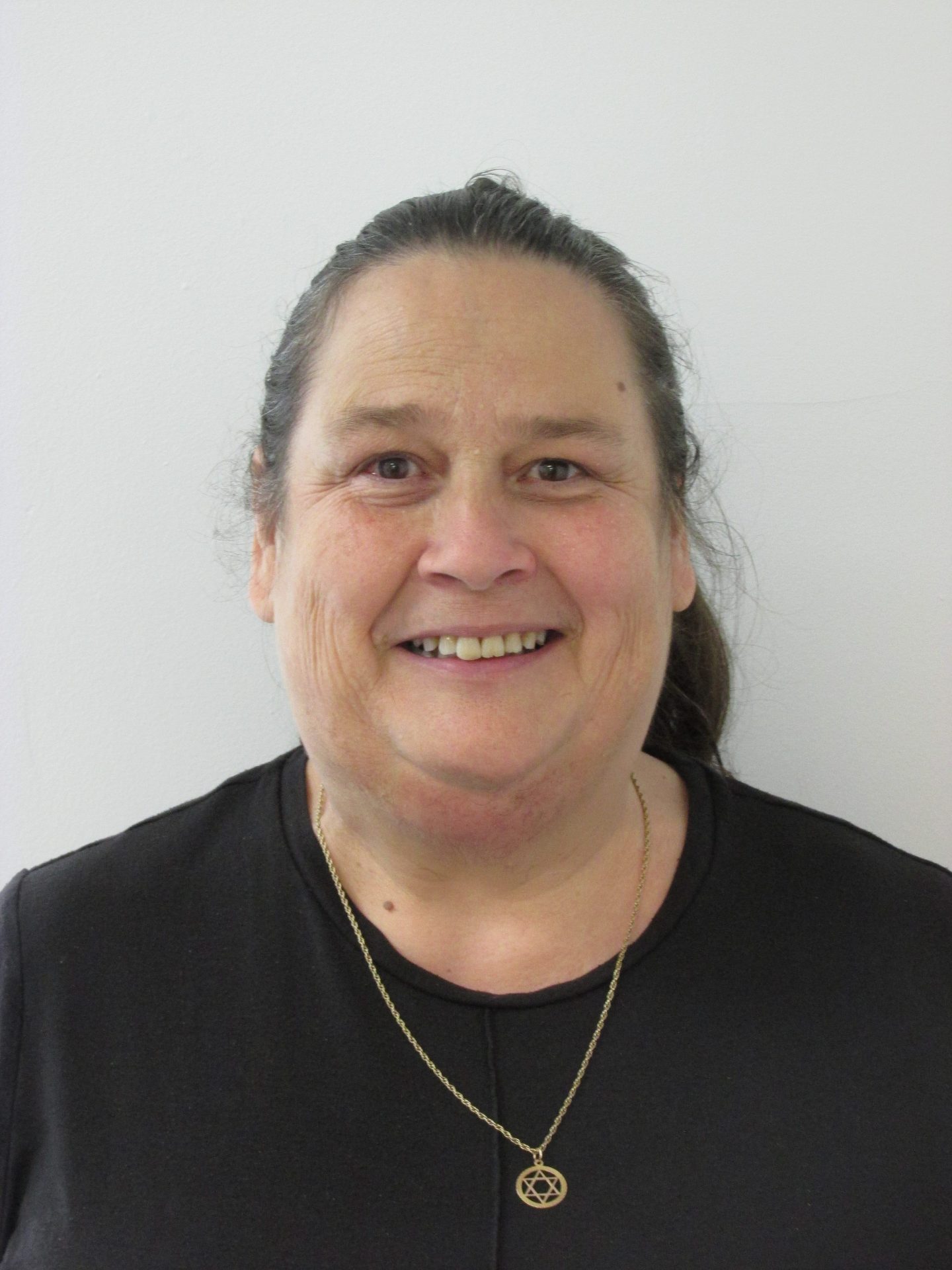 Wellbeing Support Worker Dawn Watson stood in front of white wall.